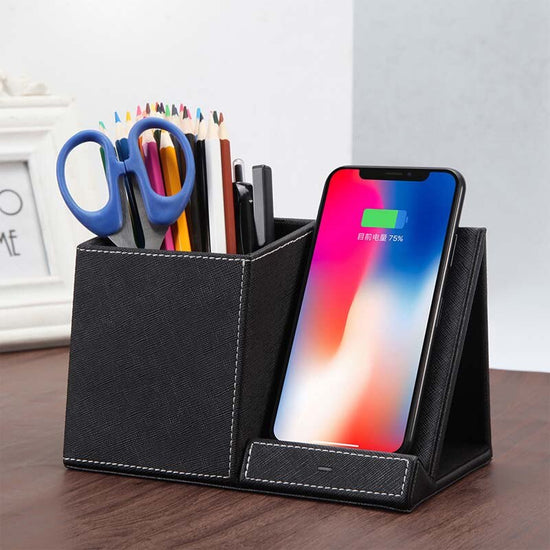 Leather pen holder wireless charger with stationery and smartphone on desk.